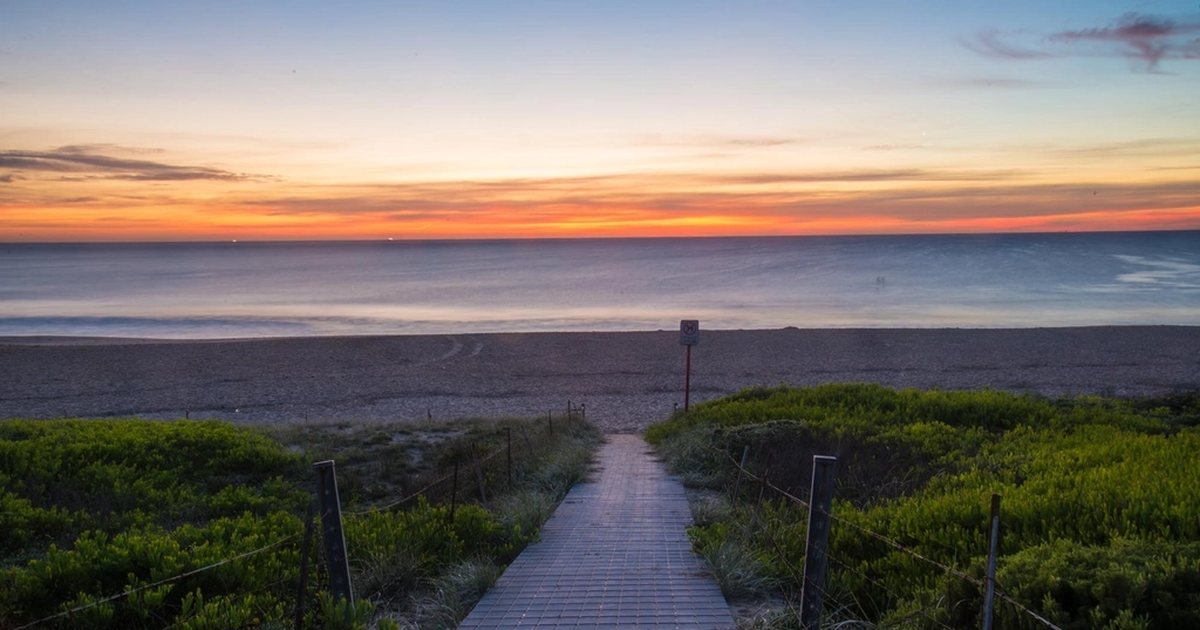 A boardwalk through the dunes to the beach at sunrise