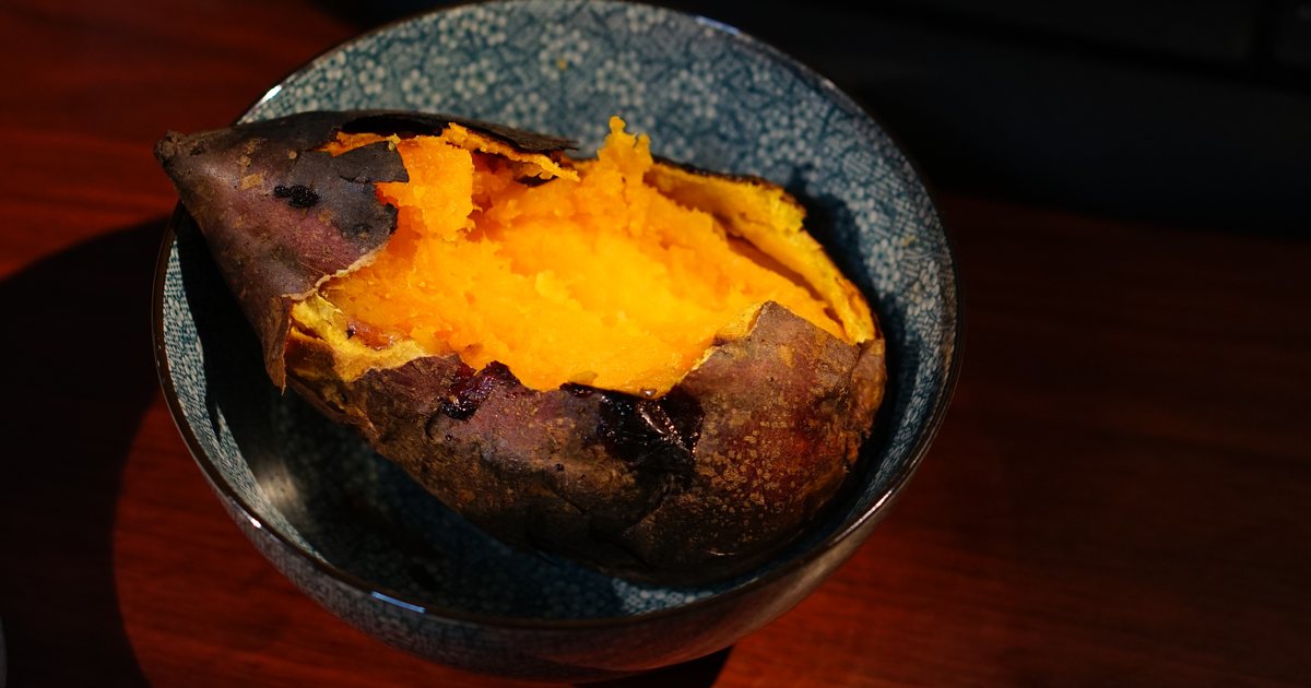 A roasted sweet potato split open in a dark bowl